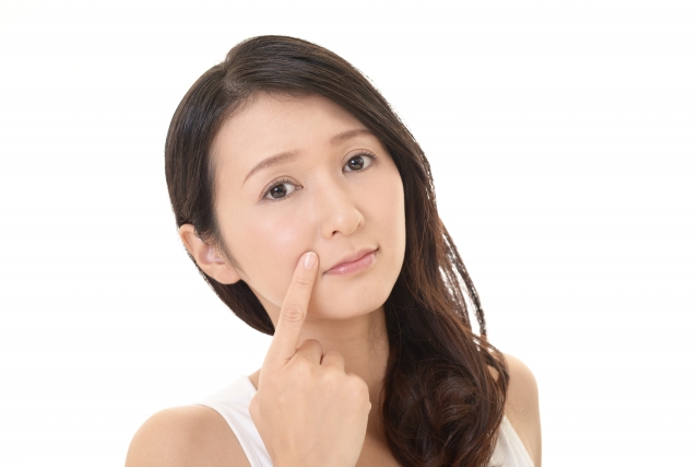 ほうれい線を指で押さえる女性